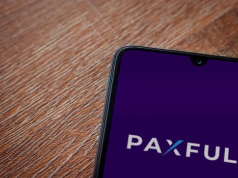 Lod, Israel - July 16,2023: Paxful app launch screen on smartphone on wooden background. Top view flat lay with copy space.