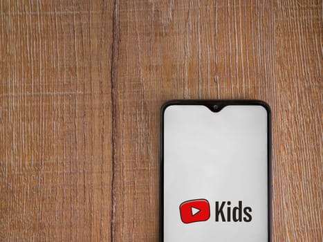 Lod, Israel - July 16,2023: YouTube Kids app launch screen on smartphone on wooden background. Top view flat lay with copy space.