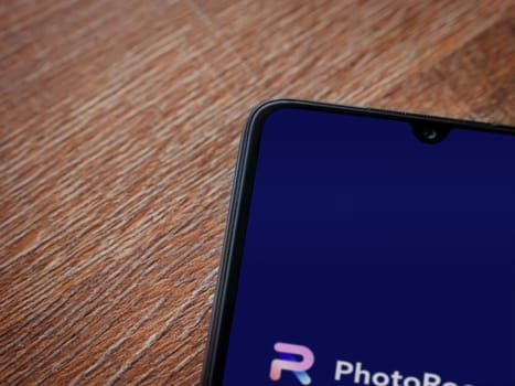 Lod, Israel - July 16,2023: PhotoRoom Studio Photo Editor app launch screen on smartphone on wooden background.. Top view flat lay with copy space.