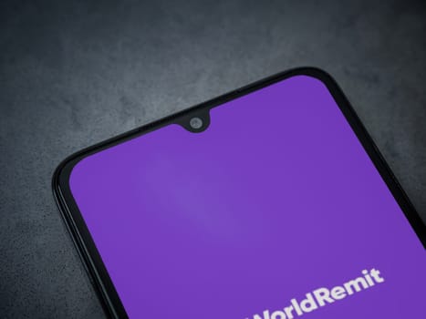 Lod, Israel - July 16,2023: WorldRemit app launch screen on smartphone on dark marble stone background. Top view flat lay with copy space.