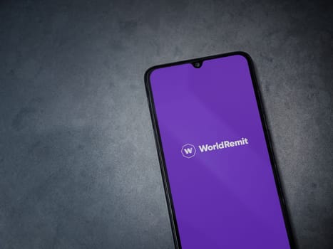 Lod, Israel - July 16,2023: WorldRemit app launch screen on smartphone on dark marble stone background. Top view flat lay with copy space.