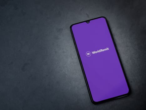 Lod, Israel - July 16,2023: WorldRemit app launch screen on smartphone on dark marble stone background. Top view flat lay with copy space.