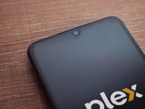 Lod, Israel - July 16,2023: Plex app launch screen on smartphone on wooden background. Top view flat lay with copy space.