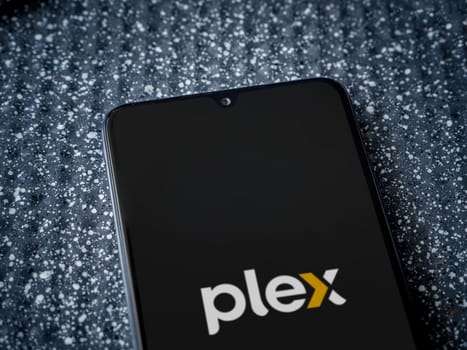 Lod, Israel - July 16,2023: Plex app launch screen on smartphone on metallic background. Close up top view flat lay.