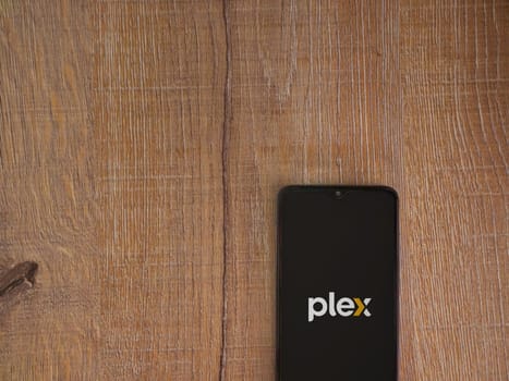 Lod, Israel - July 16,2023: Plex app launch screen on smartphone on wooden background. Top view flat lay with copy space.