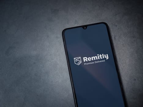 Lod, Israel - July 16,2023: Remitly app launch screen on smartphone on dark marble stone background. Top view flat lay with copy space.