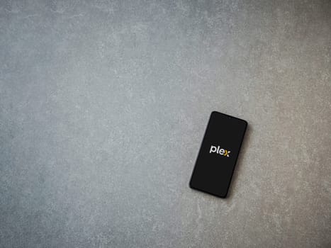 Lod, Israel - July 16,2023: Plex app launch screen on smartphone on ceramic stone background. Top view flat lay with copy space.