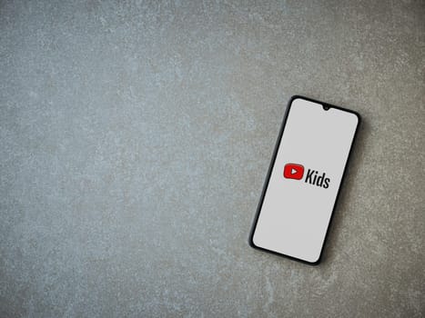 Lod, Israel - July 16,2023: YouTube Kids app launch screen on smartphone on ceramic stone background. Top view flat lay with copy space.