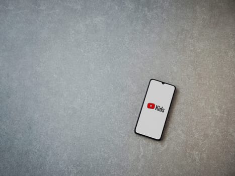 Lod, Israel - July 16,2023: YouTube Kids app launch screen on smartphone on ceramic stone background. Top view flat lay with copy space.