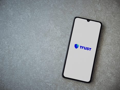 Lod, Israel - July 16,2023: Trust Wallet app launch screen on smartphone on ceramic stone background. Top view flat lay with copy space.