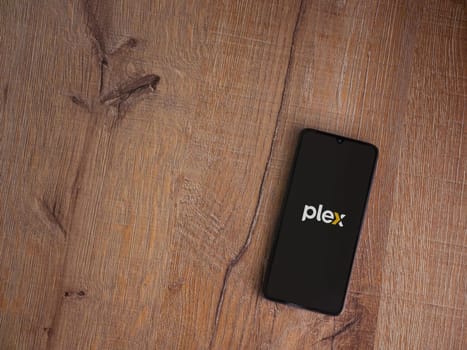 Lod, Israel - July 16,2023: Plex app launch screen on smartphone on wooden background. Top view flat lay with copy space.