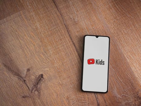 Lod, Israel - July 16,2023: YouTube Kids app launch screen on smartphone on wooden background. Top view flat lay with copy space.
