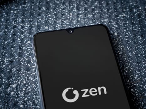 Lod, Israel - July 16,2023: ZEN.COM app launch screen on smartphone on metallic background. Close up top view flat lay.