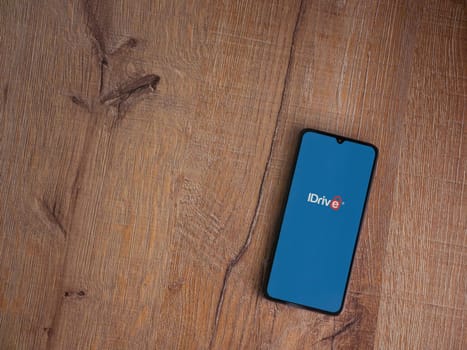 Lod, Israel - July 16,2023: IDrive Online Backup app launch screen on smartphone on wooden background. Top view flat lay with copy space.