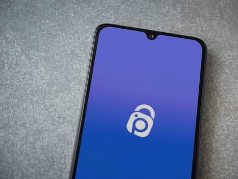 Lod, Israel - July 16,2023: IDrive Photo Backup app launch screen on smartphone on ceramic stone background. Top view flat lay with copy space.