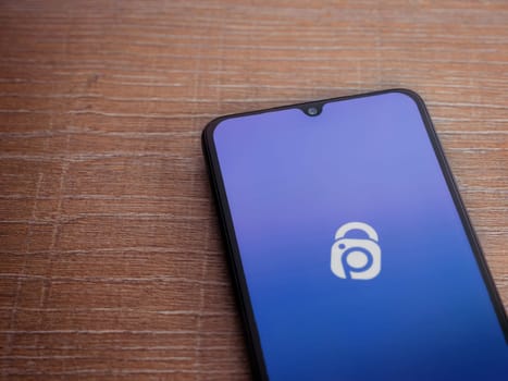 Lod, Israel - July 16,2023: IDrive Photo Backup app launch screen on smartphone on wooden background. Top view flat lay with copy space.