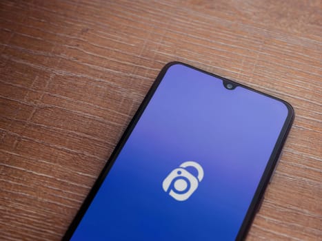 Lod, Israel - July 16,2023: IDrive Photo Backup app launch screen on smartphone on wooden background. Top view flat lay with copy space.