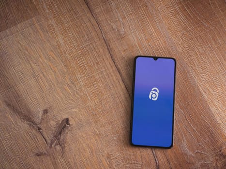 Lod, Israel - July 16,2023: IDrive Photo Backup app launch screen on smartphone on wooden background. Top view flat lay with copy space.