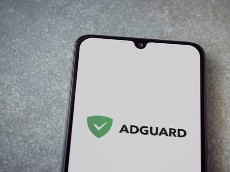 Lod, Israel - July 16,2023: AdGuard app launch screen on smartphone on ceramic stone background. Top view flat lay with copy space.