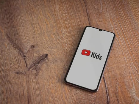 Lod, Israel - July 16,2023: YouTube Kids app launch screen on smartphone on wooden background. Top view flat lay with copy space.