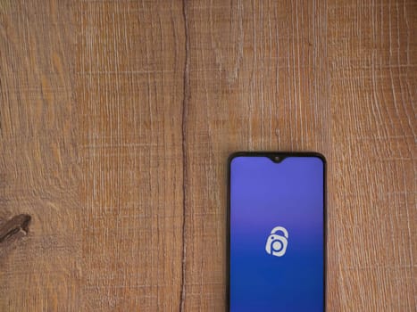 Lod, Israel - July 16,2023: IDrive Photo Backup app launch screen on smartphone on wooden background. Top view flat lay with copy space.