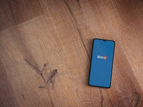 Lod, Israel - July 16,2023: IDrive Online Backup app launch screen on smartphone on wooden background. Top view flat lay with copy space.