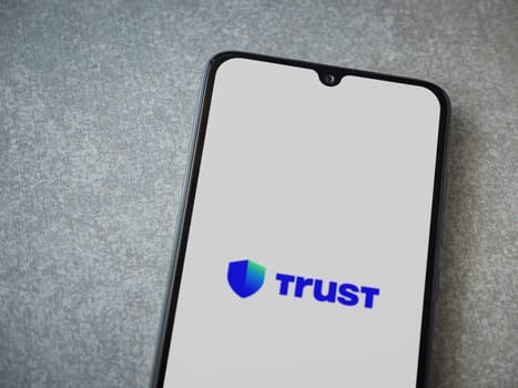 Lod, Israel - July 16,2023: Trust Wallet app launch screen on smartphone on ceramic stone background. Top view flat lay with copy space.