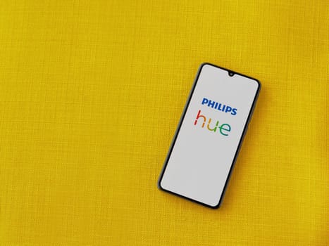 Lod, Israel - July 16,2023: Philips Hue app launch screen on smartphone on yellow fabric background. Top view flat lay with copy space.