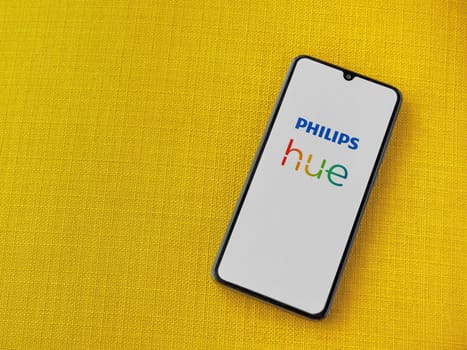 Lod, Israel - July 16,2023: Philips Hue app launch screen on smartphone on yellow fabric background. Top view flat lay with copy space.
