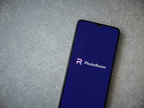 Lod, Israel - July 16,2023: PhotoRoom Studio Photo Editor app launch screen on smartphone on ceramic stone background.. Top view flat lay with copy space.