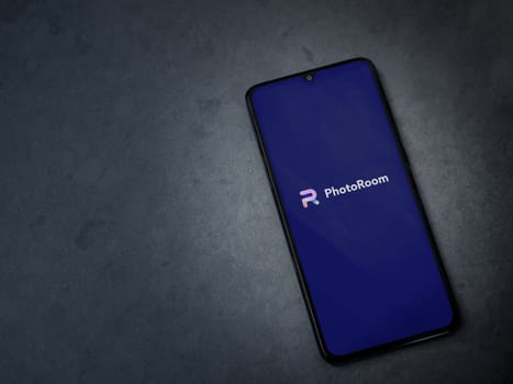 Lod, Israel - July 16,2023: PhotoRoom Studio Photo Editor app launch screen on smartphone on dark marble stone background. Top view flat lay with copy space.
