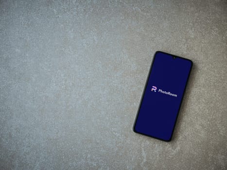 Lod, Israel - July 16,2023: PhotoRoom Studio Photo Editor app launch screen on smartphone on ceramic stone background.. Top view flat lay with copy space.