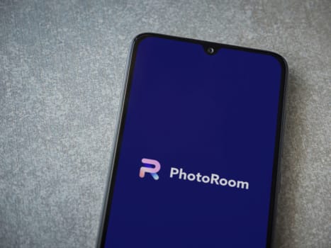 Lod, Israel - July 16,2023: PhotoRoom Studio Photo Editor app launch screen on smartphone on ceramic stone background.. Top view flat lay with copy space.