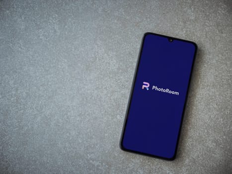 Lod, Israel - July 16,2023: PhotoRoom Studio Photo Editor app launch screen on smartphone on ceramic stone background. Top view flat lay with copy space.