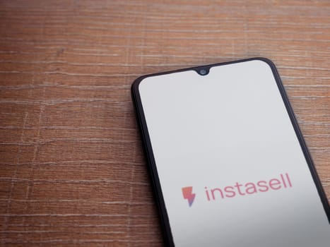 Lod, Israel - July 16,2023: Instasell app launch screen on smartphone on wooden background. Top view flat lay with copy space.