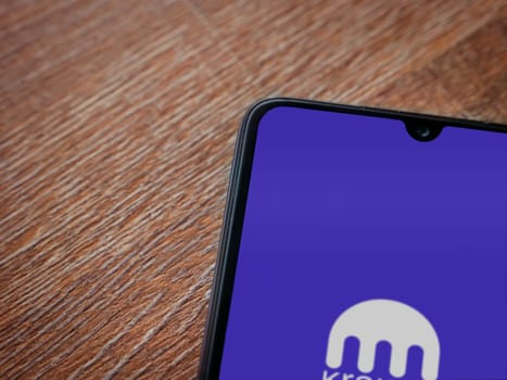 Lod, Israel - July 16,2023: Kraken app launch screen on smartphone on wooden background. Top view flat lay with copy space.