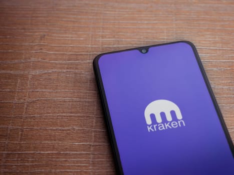 Lod, Israel - July 16,2023: Kraken app launch screen on smartphone on wooden background. Top view flat lay with copy space.
