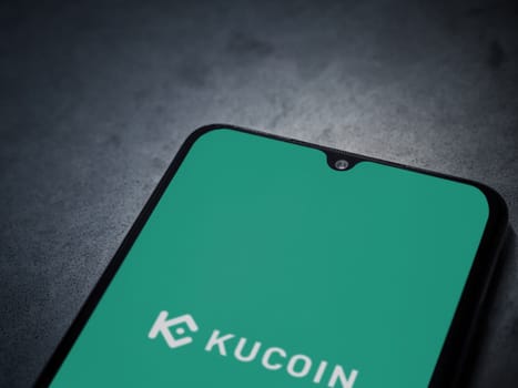 Lod, Israel - July 16,2023: KuCoin app launch screen on smartphone on dark marble stone background. Top view flat lay with copy space.