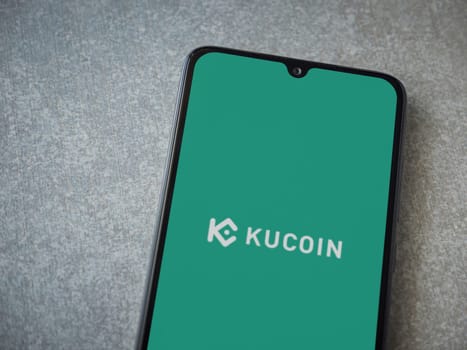 Lod, Israel - July 16,2023: KuCoin app launch screen on smartphone on ceramic stone background. Top view flat lay with copy space.