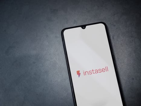 Lod, Israel - July 16,2023: Instasell app launch screen on smartphone on dark marble stone background. Top view flat lay with copy space.