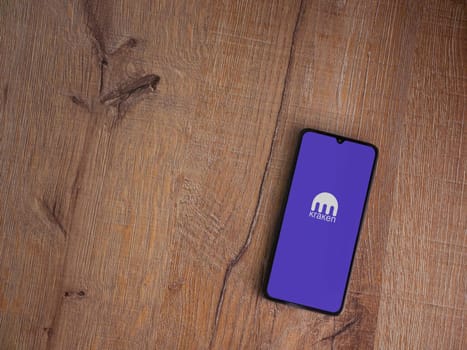 Lod, Israel - July 16,2023: Kraken app launch screen on smartphone on wooden background. Top view flat lay with copy space.