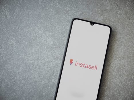 Lod, Israel - July 16,2023: Instasell app launch screen on smartphone on ceramic stone background. Top view flat lay with copy space.