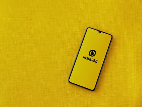 Lod, Israel - July 16,2023: Insta360 app launch screen on smartphone on yellow fabric background.. Top view flat lay with copy space.