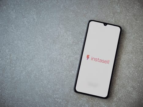 Lod, Israel - July 16,2023: Instasell app launch screen on smartphone on ceramic stone background. Top view flat lay with copy space.