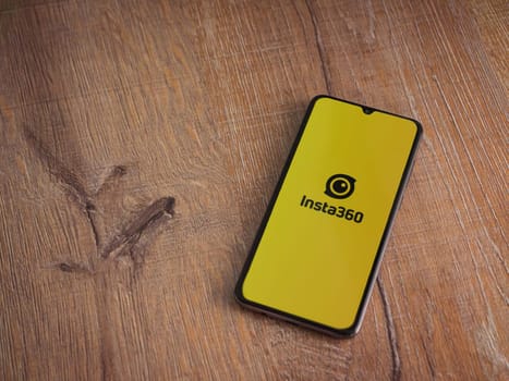 Lod, Israel - July 16,2023: Insta360 app launch screen on smartphone on wooden background.. Top view flat lay with copy space.