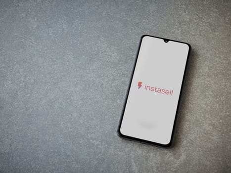 Lod, Israel - July 16,2023: Instasell app launch screen on smartphone on ceramic stone background. Top view flat lay with copy space.