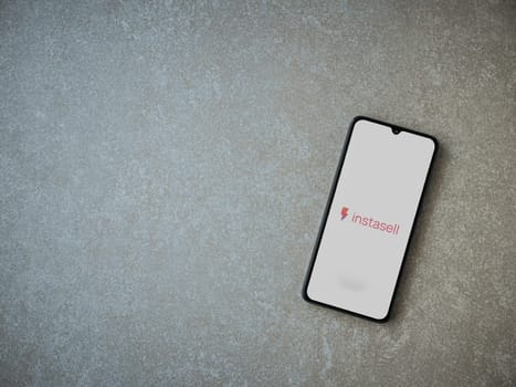 Lod, Israel - July 16,2023: Instasell app launch screen on smartphone on ceramic stone background. Top view flat lay with copy space.