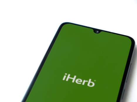 Lod, Israel - July 16,2023: iHerb app launch screen on smartphone on white background. Top view flat lay with copy space.