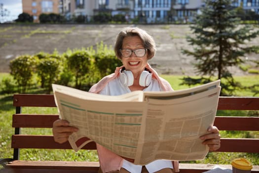 Happy elderly woman reading daily newspaper finding overwhelmed news in morning in public park