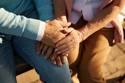 Closeup view of senior couple hands in hands together. Old man and woman giving love, support and empathy each other. Romantic date and walk for elderly people in public park